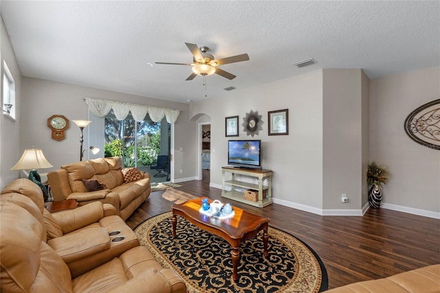 living room with a textured ceiling, dark hardwood / wood-style flooring, and ceiling fan