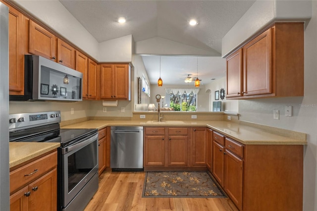 kitchen featuring sink, vaulted ceiling, ceiling fan, light wood-type flooring, and stainless steel appliances