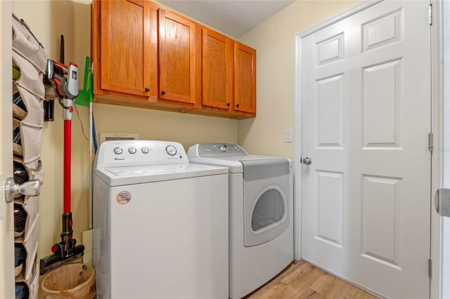 laundry area featuring cabinets, light hardwood / wood-style flooring, and washer and dryer