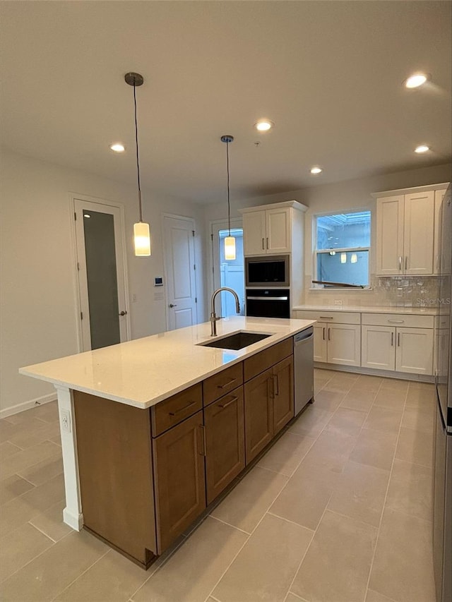 kitchen featuring appliances with stainless steel finishes, a center island with sink, white cabinetry, and sink