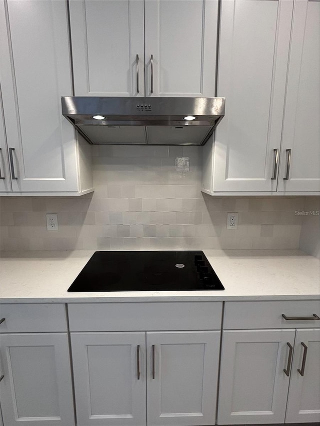 kitchen with white cabinets, black electric stovetop, and decorative backsplash