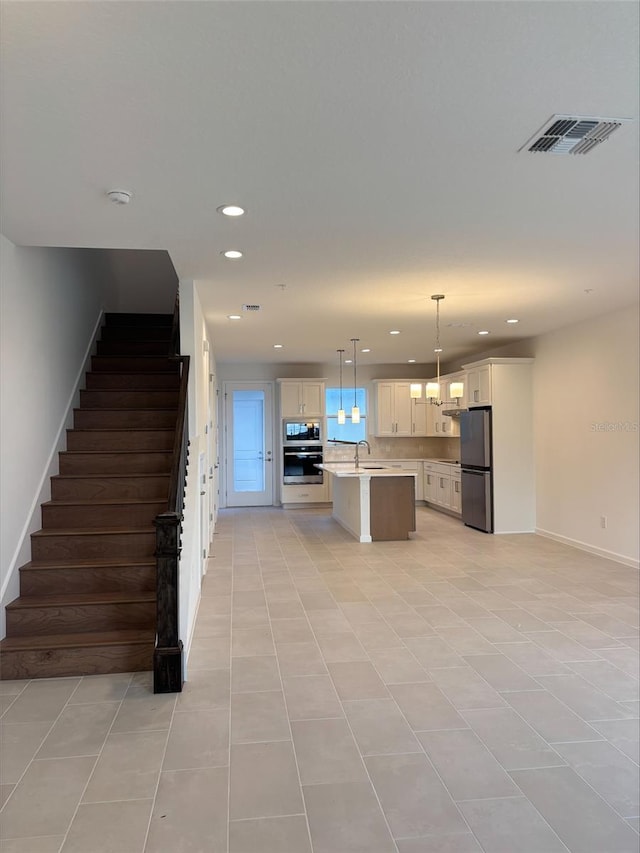 kitchen featuring stainless steel appliances, sink, pendant lighting, light tile patterned floors, and a kitchen island