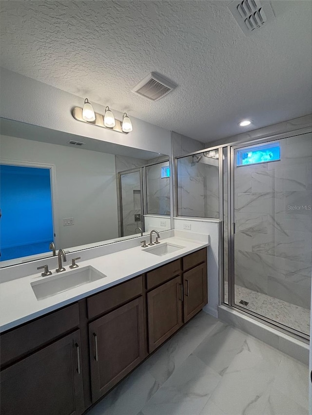 bathroom featuring vanity, an enclosed shower, and a textured ceiling