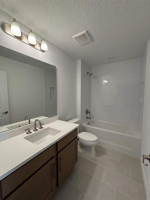 full bathroom featuring tile patterned floors, vanity, a textured ceiling, tiled shower / bath combo, and toilet