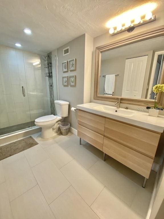 bathroom featuring tile patterned floors, a textured ceiling, vanity, toilet, and a shower with shower door