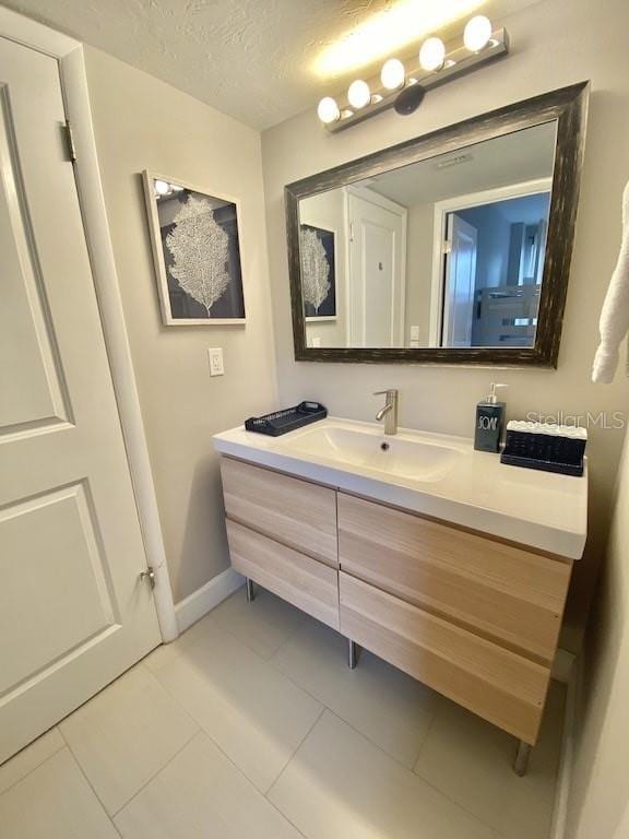 bathroom with tile patterned floors, vanity, and a textured ceiling