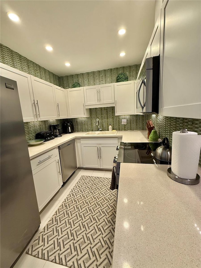 kitchen featuring white cabinets, decorative backsplash, stainless steel appliances, a sink, and recessed lighting