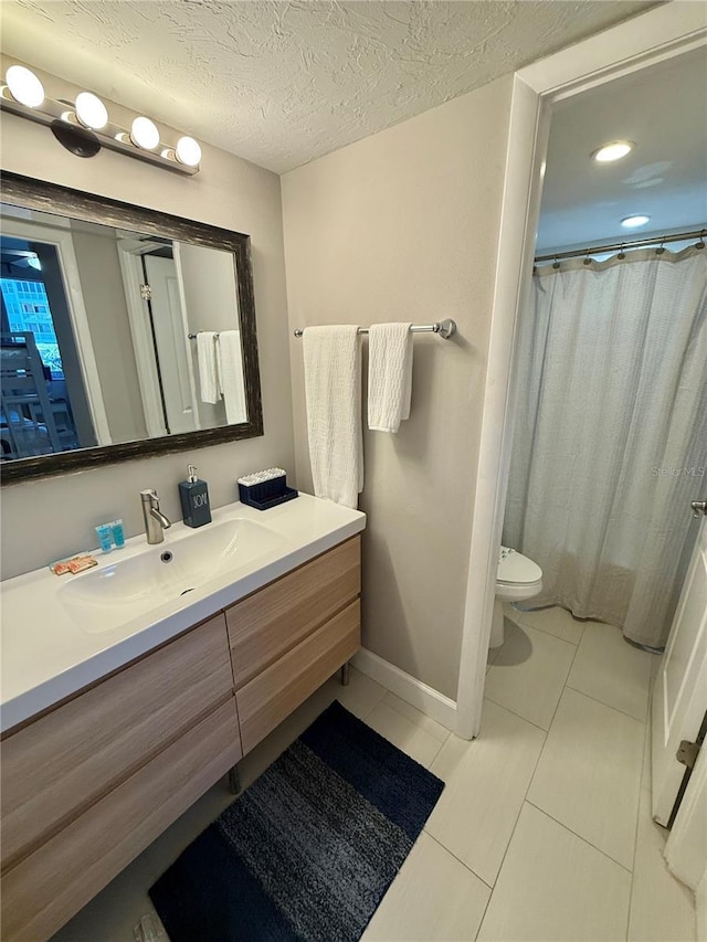 bathroom featuring toilet, a textured ceiling, vanity, tile patterned flooring, and baseboards