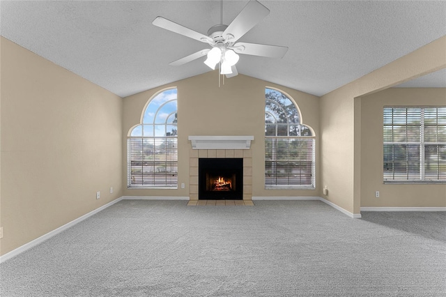 unfurnished living room with ceiling fan, light colored carpet, a textured ceiling, lofted ceiling, and a fireplace