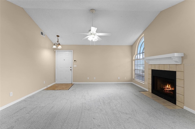 unfurnished living room featuring light colored carpet, vaulted ceiling, ceiling fan, and a tiled fireplace