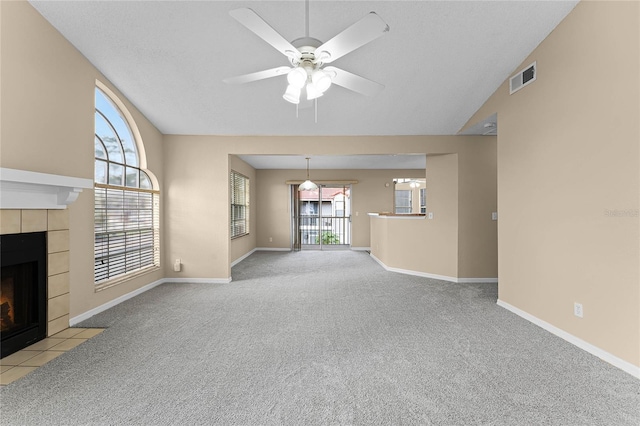 unfurnished living room featuring ceiling fan, light colored carpet, lofted ceiling, and a tile fireplace