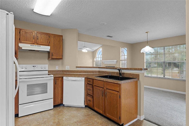 kitchen featuring kitchen peninsula, a textured ceiling, white appliances, light colored carpet, and sink