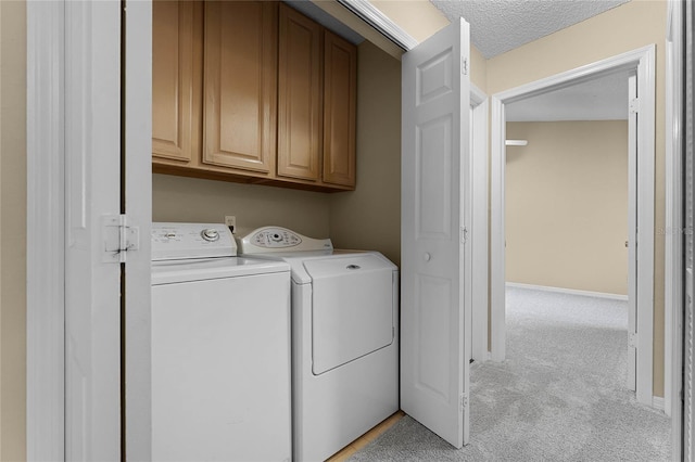 laundry room with cabinets, light carpet, a textured ceiling, and washer and dryer