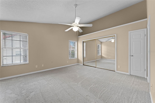 unfurnished bedroom featuring lofted ceiling, light carpet, ceiling fan, a textured ceiling, and a closet