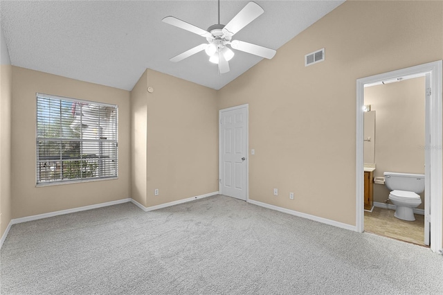 unfurnished bedroom featuring ensuite bath, a textured ceiling, light colored carpet, ceiling fan, and high vaulted ceiling