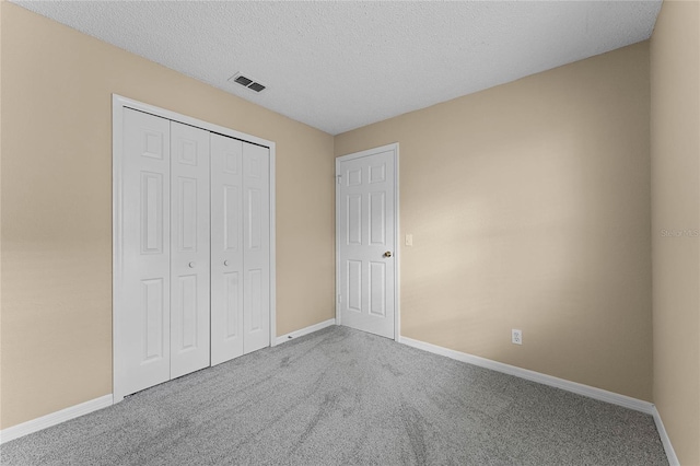 unfurnished bedroom with carpet, a textured ceiling, and a closet