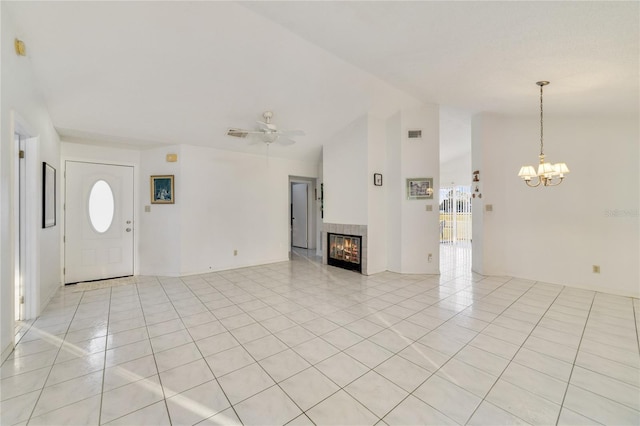 unfurnished living room featuring a tile fireplace, vaulted ceiling, light tile patterned flooring, and ceiling fan with notable chandelier