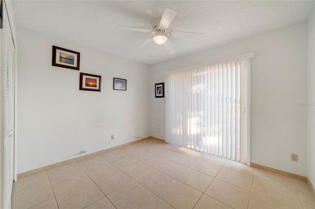 tiled empty room featuring ceiling fan and a textured ceiling