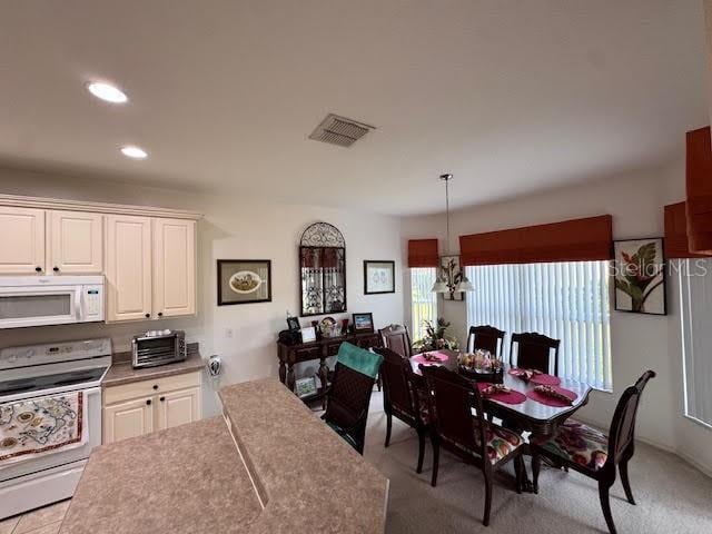 dining room with light colored carpet and an inviting chandelier