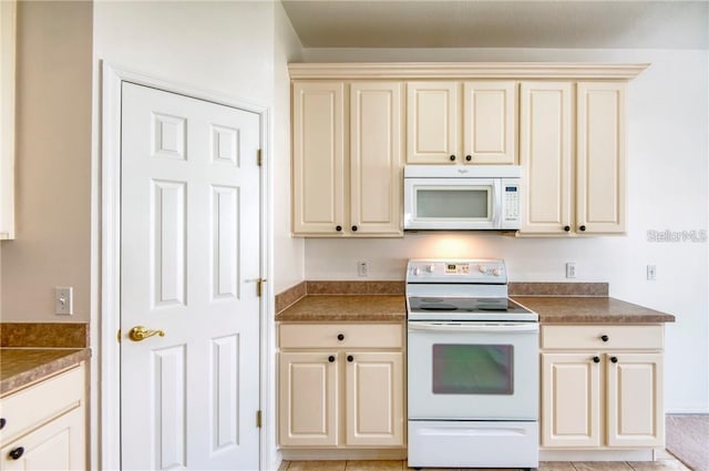 kitchen with light tile patterned floors, white appliances, and cream cabinetry