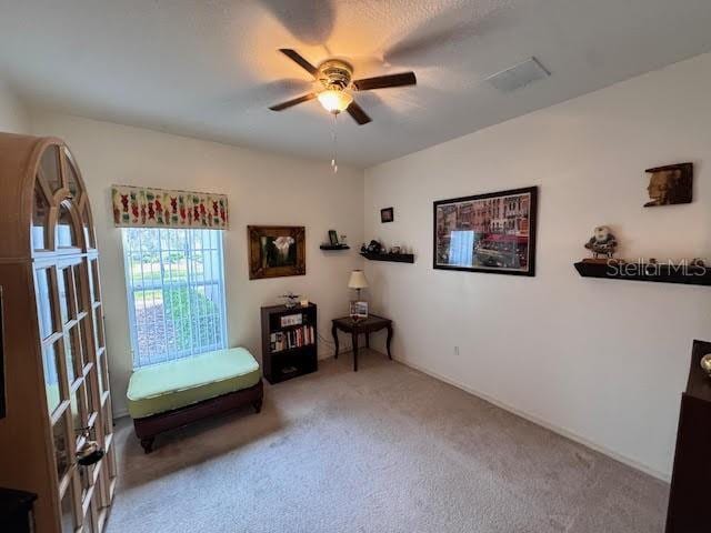 living area with carpet flooring and ceiling fan