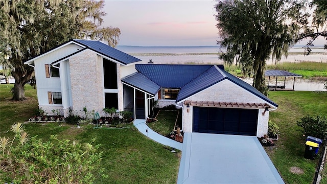 view of front facade with a yard, a water view, and a garage