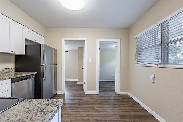 kitchen with light stone countertops, dark hardwood / wood-style flooring, white cabinets, and appliances with stainless steel finishes