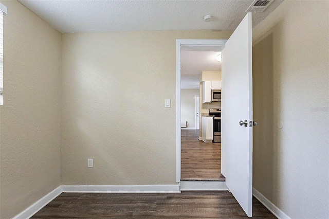 unfurnished room featuring dark hardwood / wood-style flooring and a textured ceiling