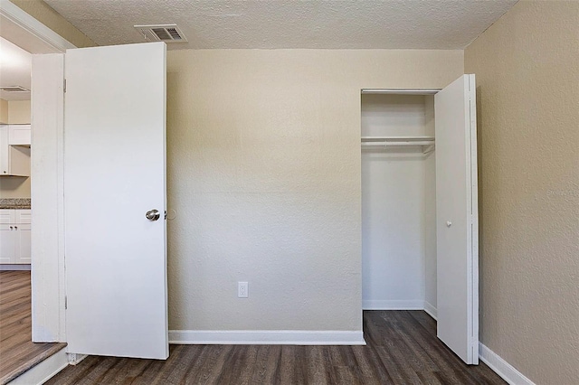 unfurnished bedroom featuring a closet, dark hardwood / wood-style flooring, and a textured ceiling