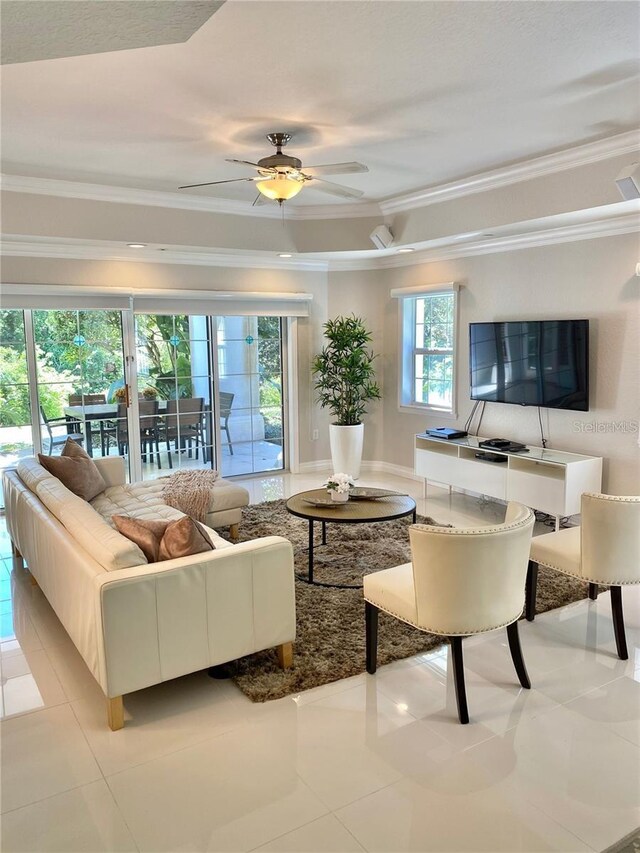 tiled living area with a ceiling fan and crown molding