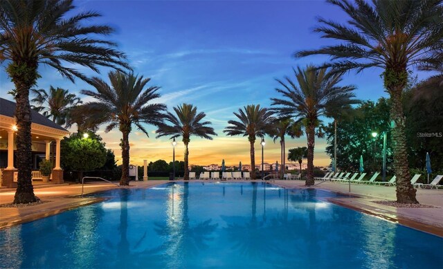 pool at dusk with a patio and a community pool