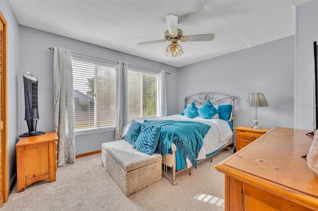 bedroom featuring light carpet, a textured ceiling, and ceiling fan