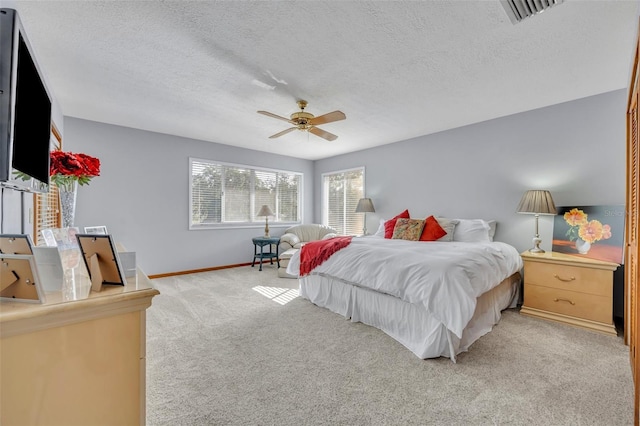 carpeted bedroom with ceiling fan and a textured ceiling