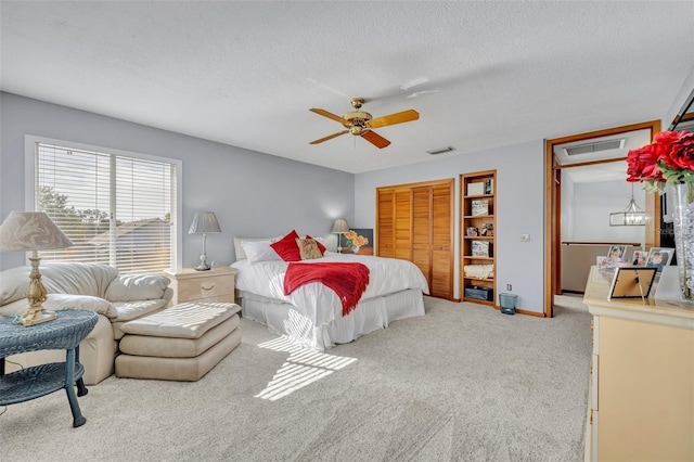 bedroom with ceiling fan, a closet, light carpet, and a textured ceiling