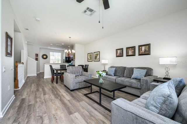 living room featuring hardwood / wood-style flooring and ceiling fan with notable chandelier