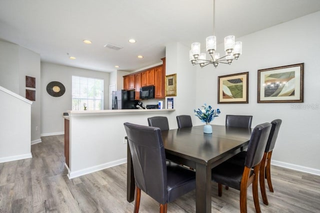 dining room with a notable chandelier and light wood-type flooring