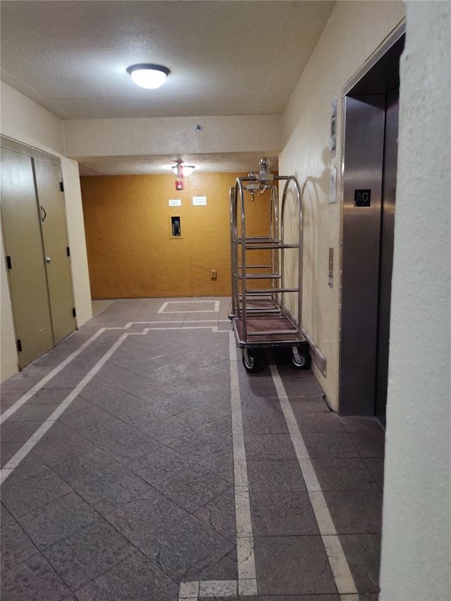 corridor featuring a textured ceiling and elevator