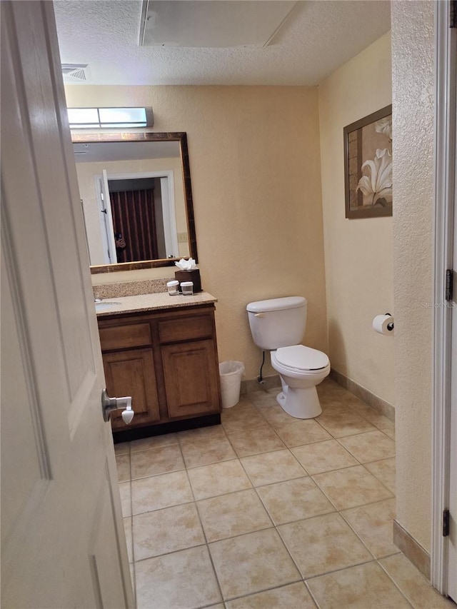 bathroom with tile patterned flooring, vanity, a textured ceiling, and toilet