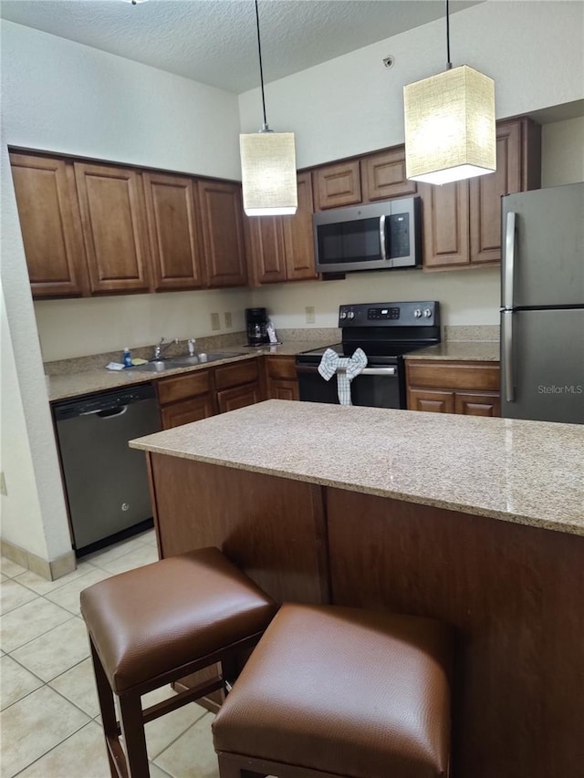 kitchen featuring light stone countertops, hanging light fixtures, a textured ceiling, light tile patterned floors, and black appliances