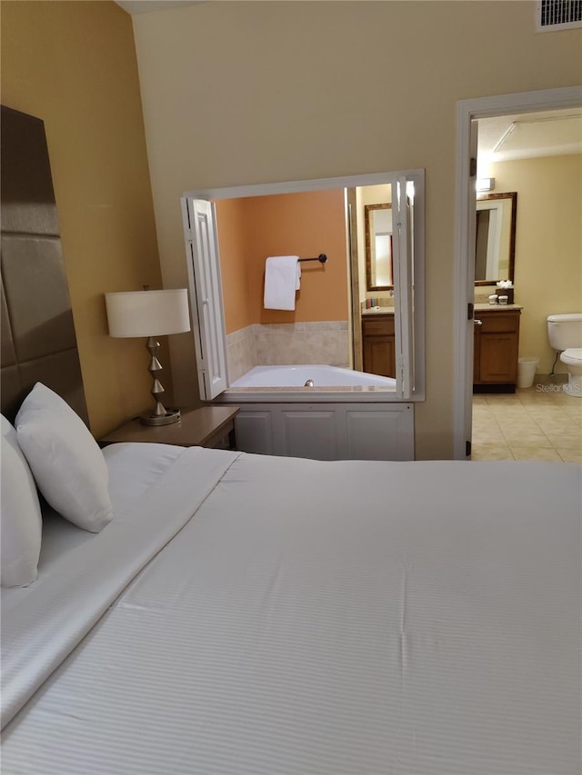 bedroom featuring connected bathroom and light tile patterned flooring