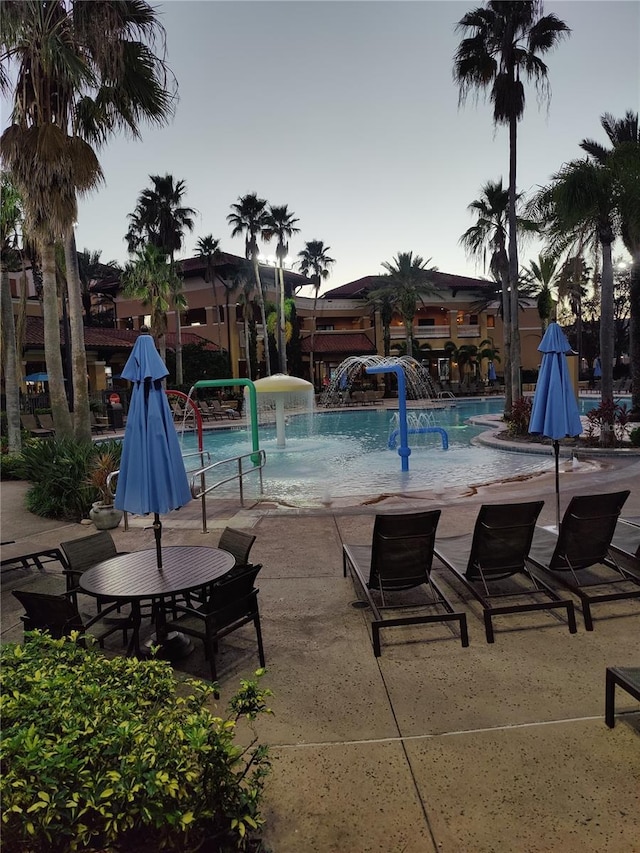 pool at dusk featuring pool water feature