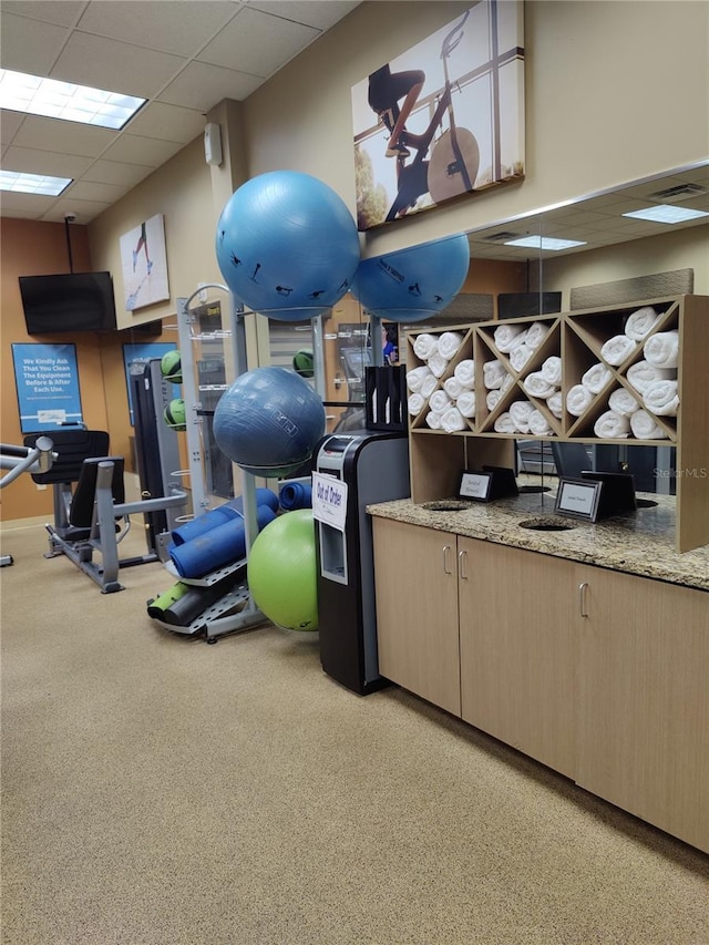 workout area with a paneled ceiling and light carpet