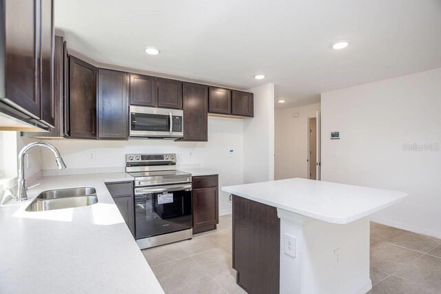 kitchen featuring dark brown cabinetry, sink, light tile patterned flooring, and stainless steel appliances