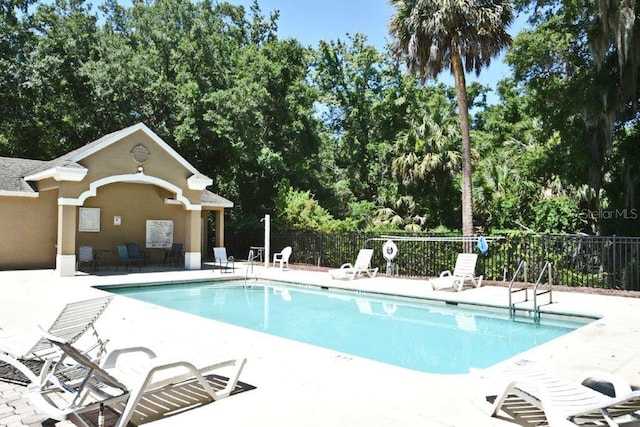 pool with a patio and fence