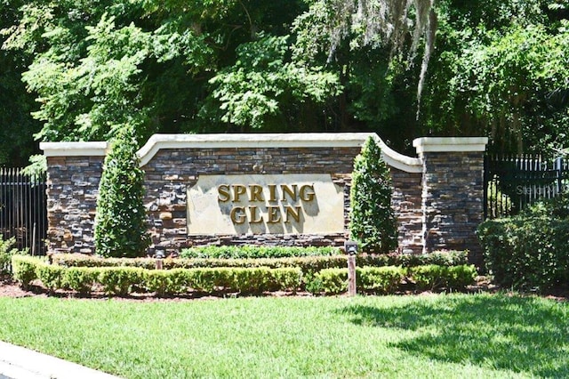 community / neighborhood sign featuring a lawn and fence