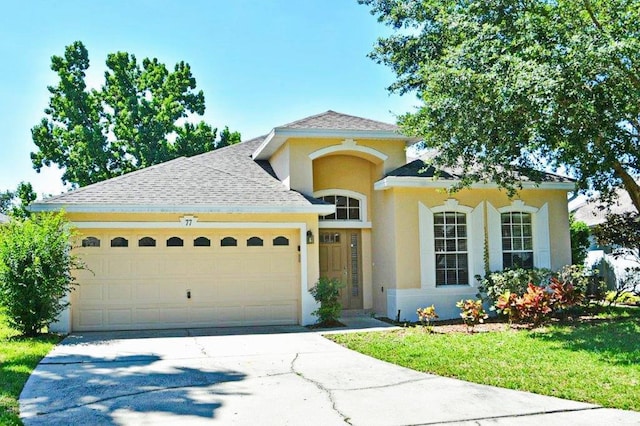 view of front of property with driveway, roof with shingles, a garage, and stucco siding