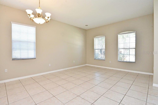 empty room featuring baseboards and a chandelier