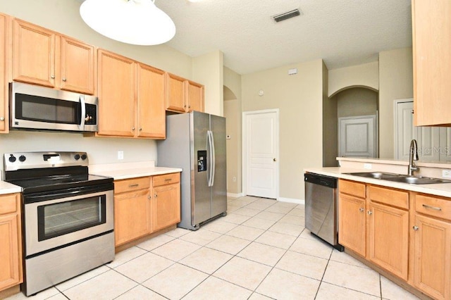 kitchen featuring light tile patterned floors, stainless steel appliances, light countertops, light brown cabinets, and a sink