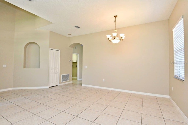 unfurnished room featuring baseboards, visible vents, arched walkways, and light tile patterned flooring