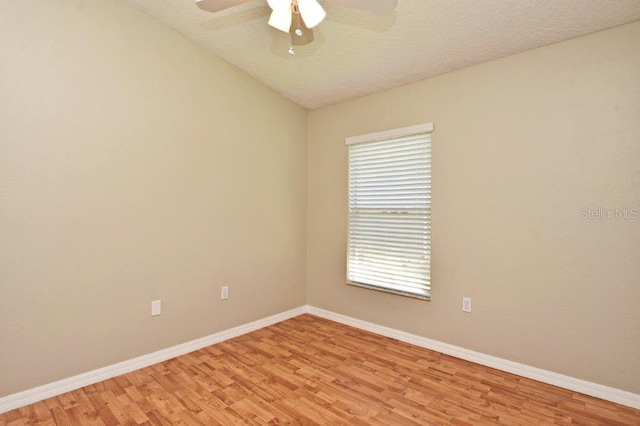 empty room featuring a textured ceiling, a ceiling fan, baseboards, vaulted ceiling, and light wood-style floors